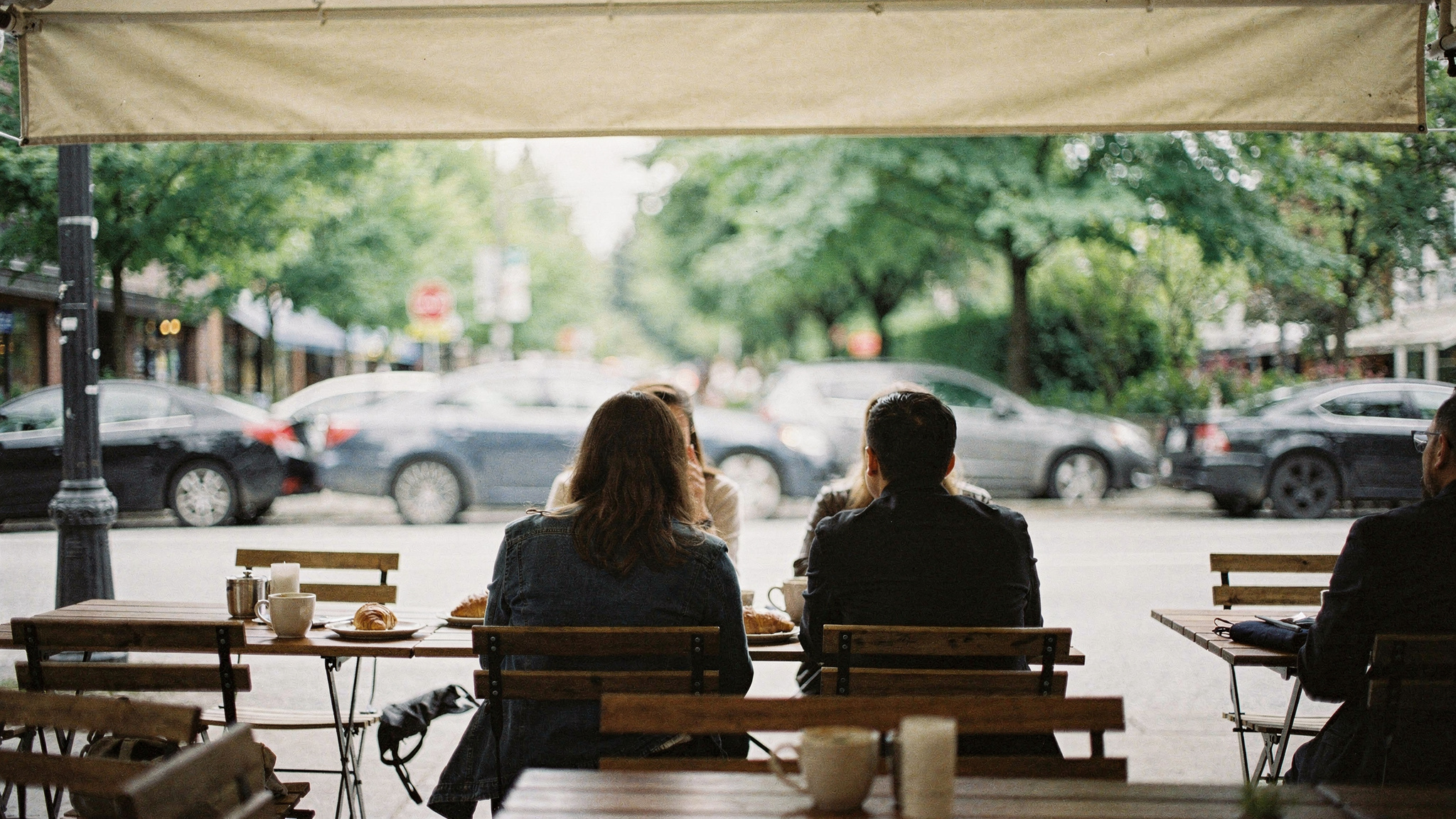 brunch hero vancouver v2 1 Best Brunch in Vancouver, BC Diners seated at an outdoor brunch patio on a tree lined Vancouver street, seen from behind